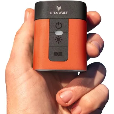 A compact orange and black device, branded \“ETENWOLF,\“ is shown held in a hand. It features a power button, a light indicator, and a lightning bolt symbol on its front panel.