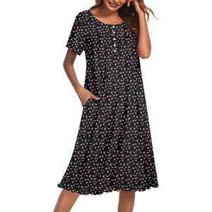 A knee-length black dress with a small floral pattern, featuring short sleeves and side pockets.