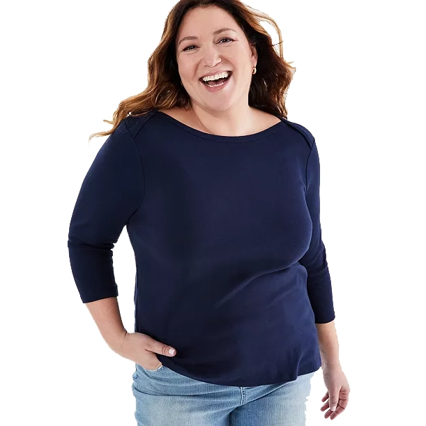 A smiling woman wearing a navy blue three-quarter sleeve top and light blue jeans.