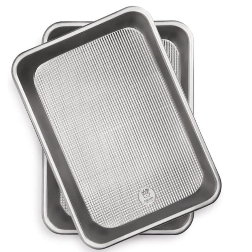 Two rimmed baking pans, each with a textured non-stick surface. They are rectangular and designed for even baking, measuring 9\“ x 13\“.
