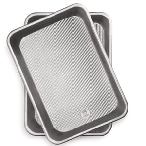 Two rimmed baking pans, each with a textured non-stick surface. They are rectangular and designed for even baking, measuring 9\“ x 13\“.