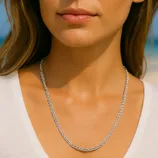 A woman wears a twisted rope-style silver necklace. She is dressed in a white shirt, showcasing the simple and elegant jewelry piece.