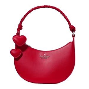 Red Kate Spade shoulder bag with a twisted strap and two heart-shaped charms.