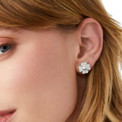 A close-up of a woman's ear wearing a flower-shaped stud earring. The earring features a simple and elegant design.