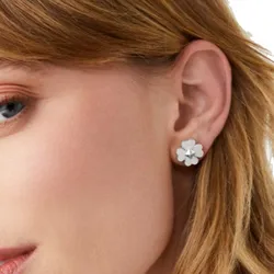 A close-up of a woman's ear wearing a flower-shaped stud earring. The earring features a simple and elegant design.