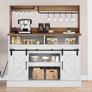 A kitchen shelf features a coffee station with a coffee maker, hanging mugs, jars, and various packaged items. Below are shelves with dishes, baskets, and sliding barn-style cabinet doors.