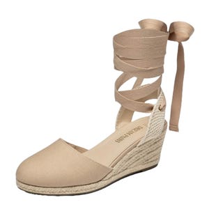 A beige wedge espadrille with ankle wrap ties and braided rope sole.