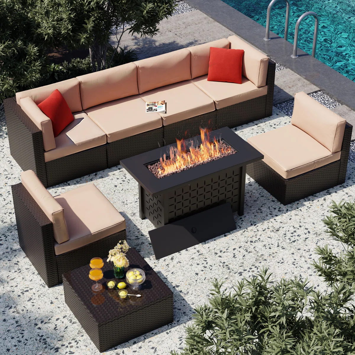 Outdoor patio set includes a sectional sofa, two chairs, a rectangular fire pit, and a small table with drinks. Sofa has beige cushions and red pillows, surrounded by plants and a pool.
