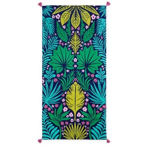 A colorful rectangular towel with a vibrant tropical leaf pattern featuring shades of green, blue, yellow, and pink on a dark blue background, accented with pink tassels at each corner.