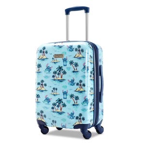 A light blue suitcase with a tropical print featuring islands and Stitch from Lilo & Stitch, equipped with wheels and an extendable handle.