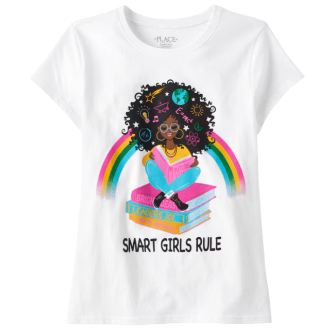 White t-shirt featuring an illustration of a girl sitting on stacked books with rainbow accents. Text reads \“SMART GIRLS RULE\“.