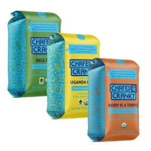 Three bags of Chafed & Cranky coffee are displayed: Inca Trail (green), Uganda (yellow), and Body is a Temple (orange). Each bag weighs 12oz and features playful designs with text describing flavor notes.