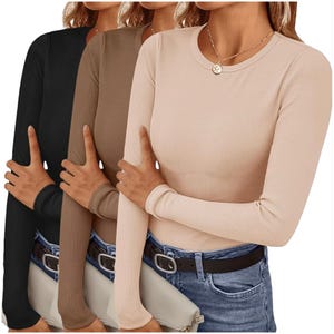 Three long-sleeve, ribbed tops in black, brown, and beige are layered over each other. They are paired with blue jeans, a black belt, and a light-colored clutch. A gold necklace adds a touch of detail to the outfit.
