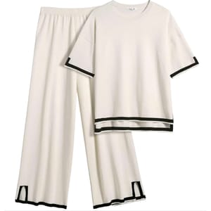 A cream-colored, two-piece lounge set featuring a short-sleeve shirt and wide-leg pants, both with black trim detailing on the hem and sleeves.