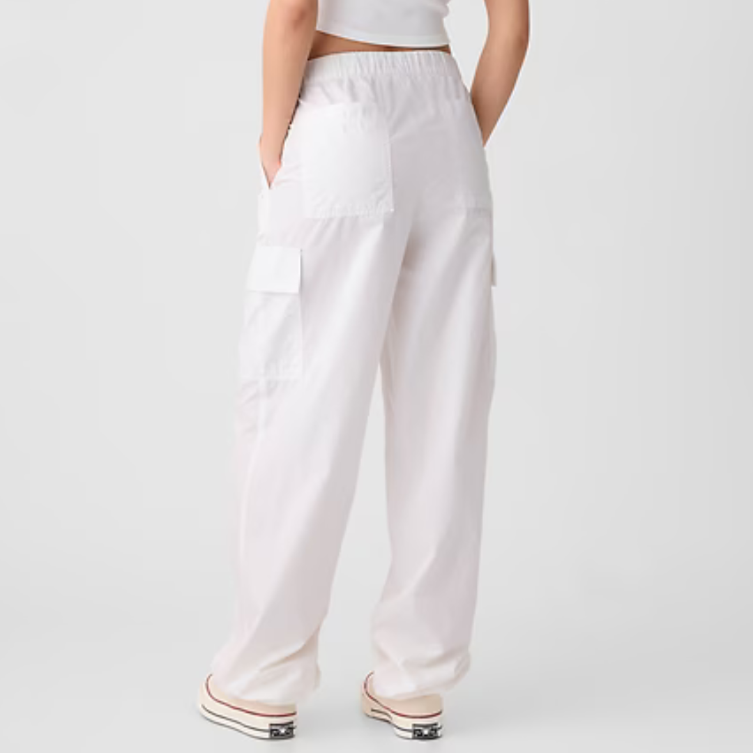 White cargo pants featuring a relaxed fit with multiple utility pockets and an elastic waistband, paired with sneakers.