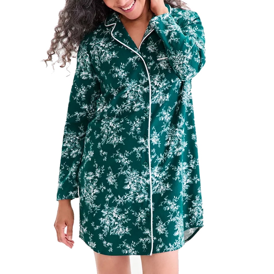 A woman is wearing a green floral-patterned, long-sleeved pajama shirt with white piping.