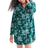 A woman is wearing a green floral-patterned, long-sleeved pajama shirt with white piping.