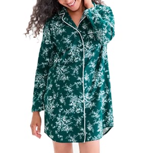 A woman is wearing a green floral-patterned, long-sleeved pajama shirt with white piping.