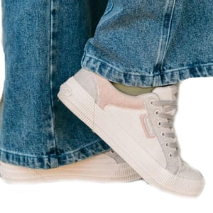 A pair of light-colored sneakers paired with wide-legged blue jeans.