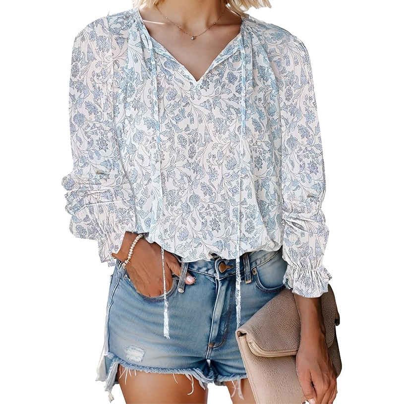Lightweight boho blouse with a blue floral pattern, featuring long sleeves with ruched cuffs and a V-neck with tassel ties, paired with distressed denim shorts.