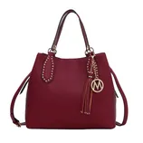 A maroon handbag with dual handles, gold-tone stud detailing, and a detachable shoulder strap. It features a decorative tassel and charm with a logo accent.