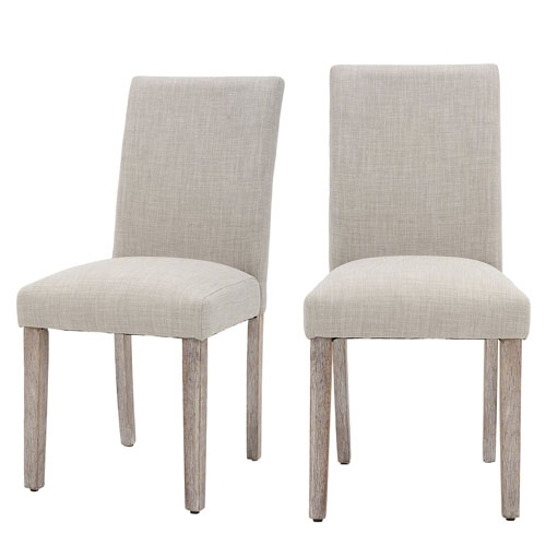 Two beige upholstered dining chairs with wooden legs and a simple, modern design.