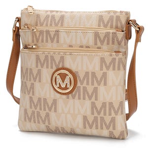 A beige crossbody bag with a brown adjustable strap, featuring a repeating \“M\“ pattern and a decorative \“M\“ emblem with rhinestones.