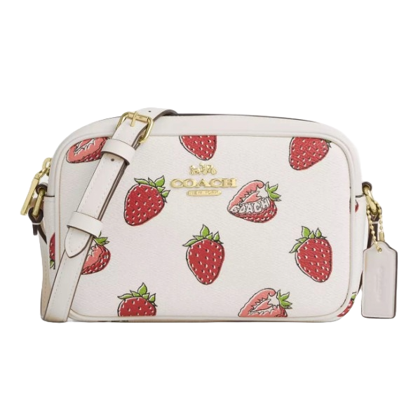 Coach Outlet Camera Bag with a white background features a strawberry print and gold-tone logo detailing. It includes an adjustable strap and a small leather tag.