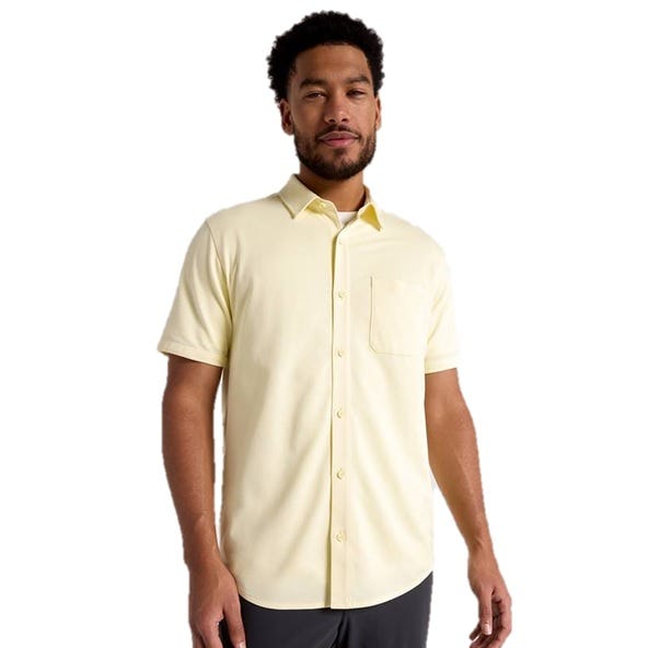 A man wearing a light yellow short-sleeve button-up shirt with a chest pocket.
