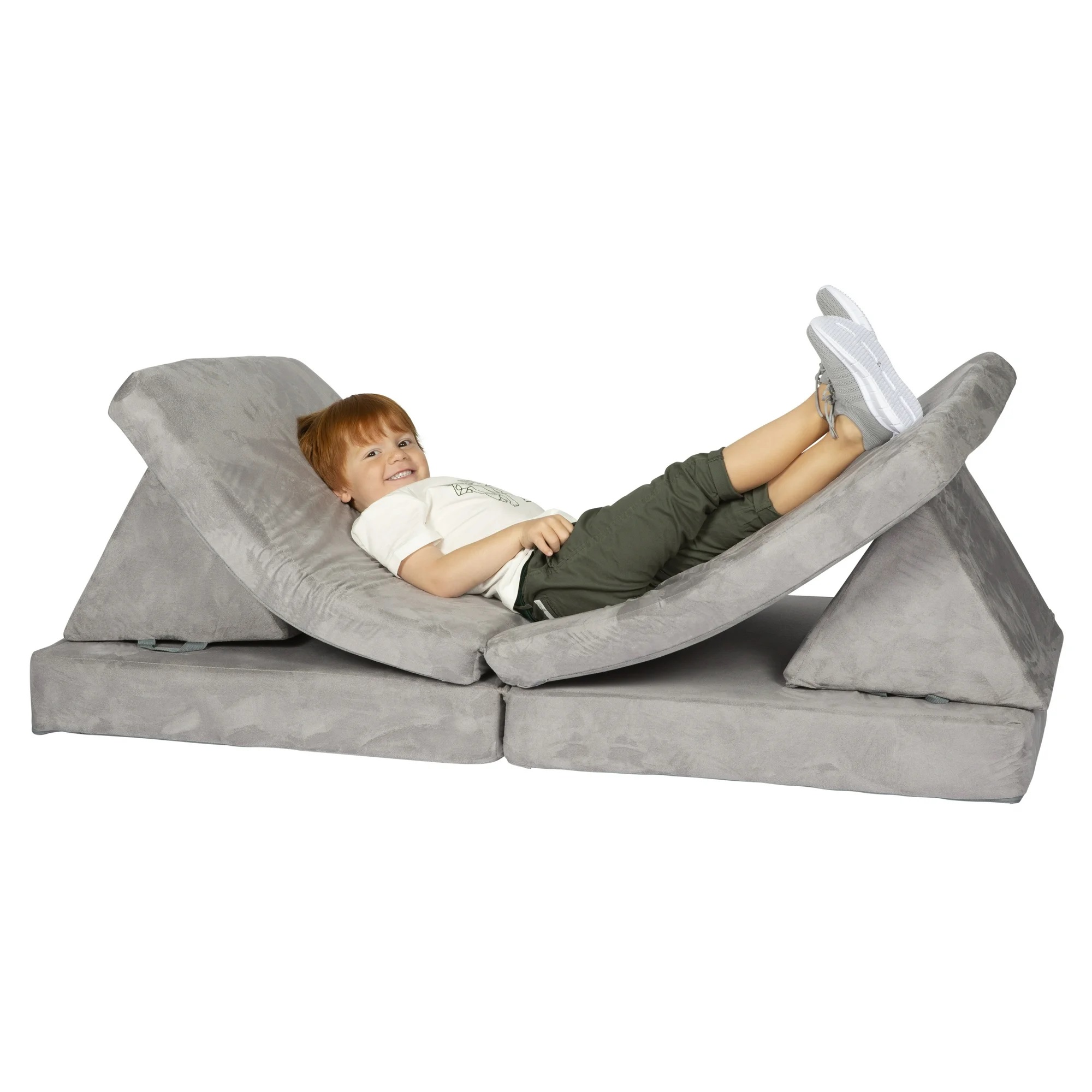 A child is lying on a light gray foam couch for kids with versatile foldable cushions that can be arranged in various shapes for seating or lounging.