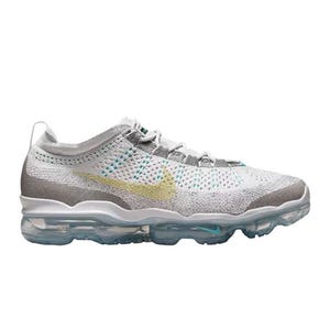 Nike Air VaporMax features a sleek, low-top design with a white and gray knit upper, transparent Air cushioning soles, and a subtle yellow Swoosh logo.