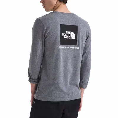 Man wearing a gray long-sleeve shirt with The North Face logo and the phrase \“Never Stop Exploring\“ on the back.