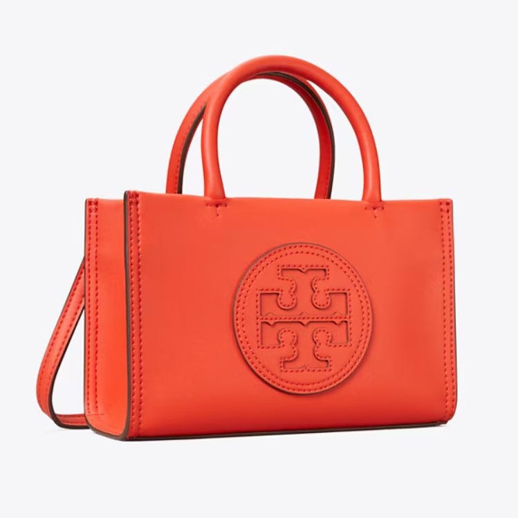 A bright orange, structured leather handbag with a prominent embossed logo on the side.