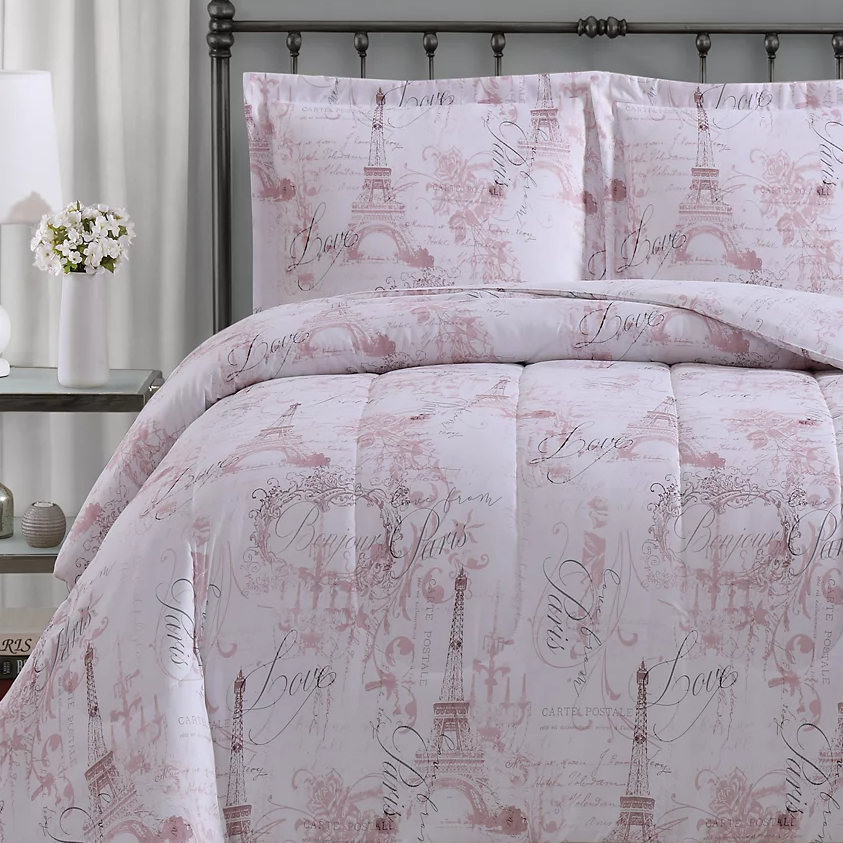 Bedding set featuring a Paris theme with the Eiffel Tower and scripted words like \“Love\“ and \“Bonjour Paris\“ in a soft pink and white design.