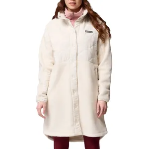 A woman wearing a long, off-white fleece coat with quilted upper detailing and snap buttons, displaying a Columbia logo on the chest.