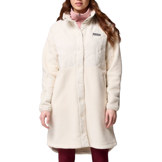 A woman wearing a long, off-white fleece coat with quilted upper detailing and snap buttons, displaying a Columbia logo on the chest.