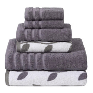 A stack of towels in shades of grey and white, featuring a leaf pattern on some, with varying sizes for different uses.