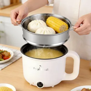 A kitchen appliance is steaming corn and buns in a stainless steel tray above a rice or porridge cooking section. A side dish of vegetables and proteins is visible on the table.