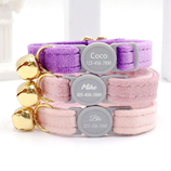 Three cat collars with bells are stacked, each featuring a name and phone number: \“Coco\“ on a purple collar, \“Mike\“ on a pink collar, and \“Blu\“ on a light pink collar.