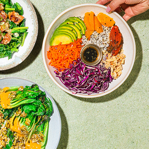 The image shows vibrant plant-based meals with ingredients like avocado, carrots, purple cabbage, leafy greens, and a variety of grains with a sauce. The dishes appear colorful and healthy, featuring diverse textures and flavors.