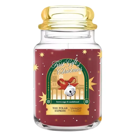 Yankee Candle x The Polar Express \“First Gift of Christmas,\“ scented with brown sugar and sandalwood, in a decorative jar with festive imagery and a bell motif.