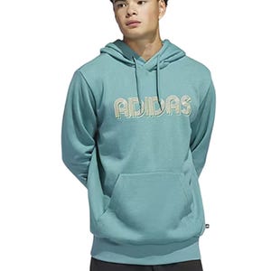 A person wears a teal Adidas hoodie with a kangaroo pocket and the brand name in bold, stylized text on the chest.