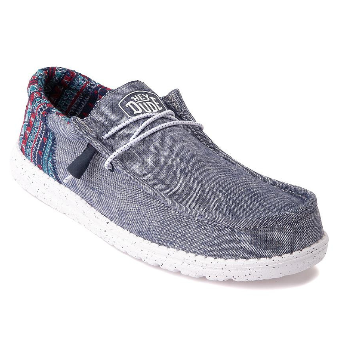 A casual, slip-on shoe with a denim-style fabric upper and a white, splotched sole.