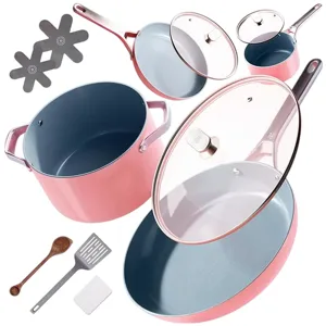 A pink cookware set including various pots and pans with lids, a wooden spoon, metal spatula, and two protective pads for stacking.