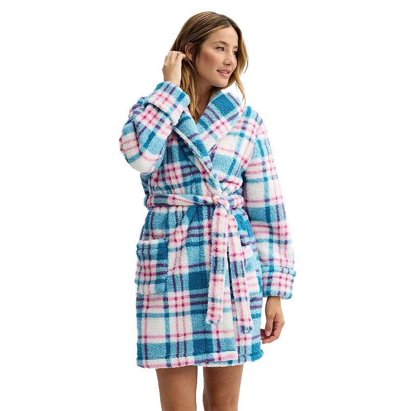 A woman wears a Sonoma plush robe, featuring a pink, blue, and white plaid pattern. The robe includes a shawl collar, a waist tie belt, and front pockets.