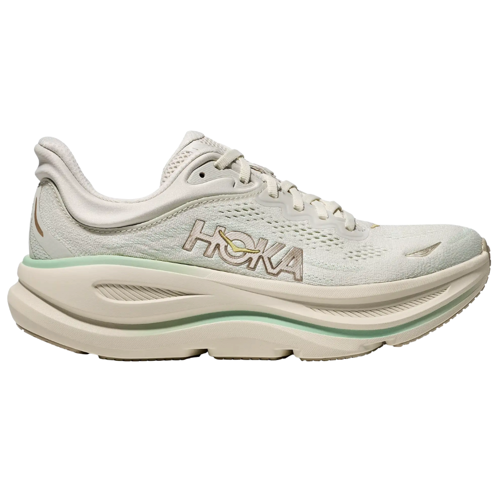 Hoka running shoe in a light cream color with green accents and cushioned sole, featuring a breathable mesh upper and Hoka logo on the side.
