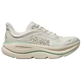 Hoka running shoe in a light cream color with green accents and cushioned sole, featuring a breathable mesh upper and Hoka logo on the side.