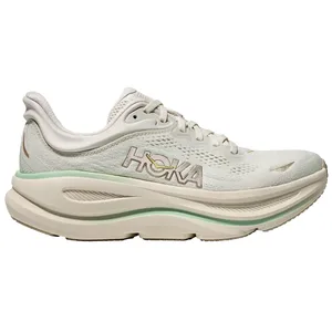 Hoka running shoe in a light cream color with green accents and cushioned sole, featuring a breathable mesh upper and Hoka logo on the side.