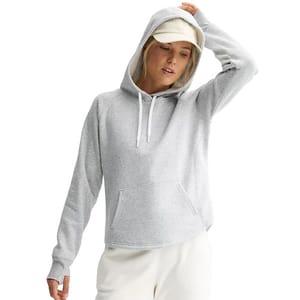 A person wearing a gray hoodie with a front pocket and a drawstring hood, paired with a light-colored cap and pants.