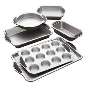 A set of nonstick baking pans includes a muffin pan, two rectangular baking pans, a circular cake pan, and two loaf pans, each with silicone handles for easy grip.
